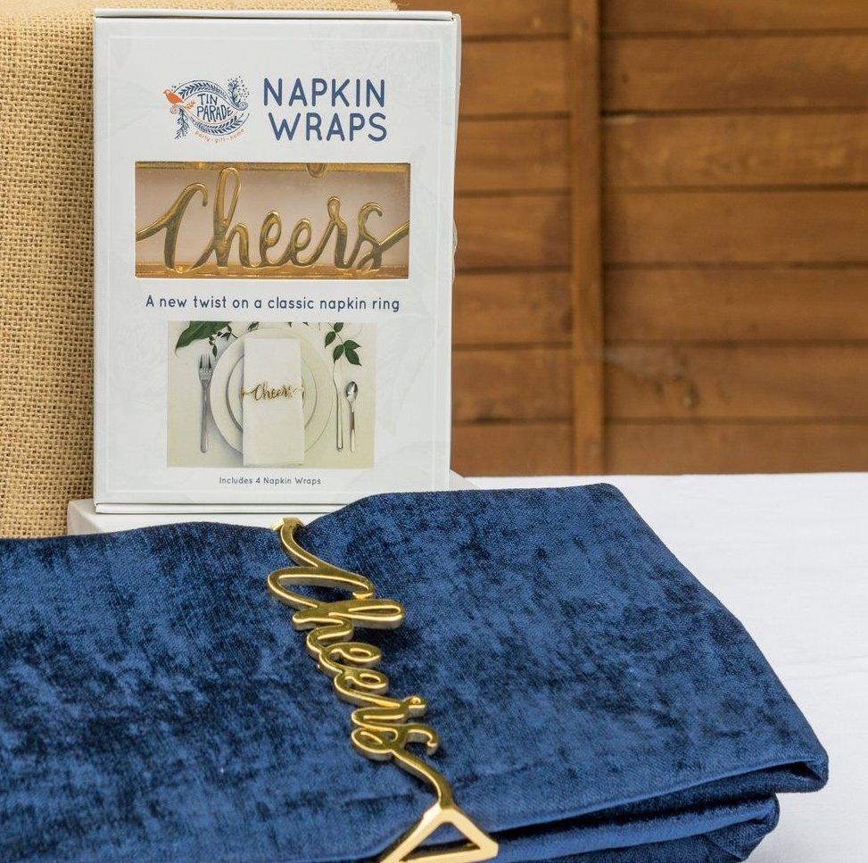 Set of 4 shiny gold napkin wraps with 'cheers' design, elegantly displayed on a dining table.