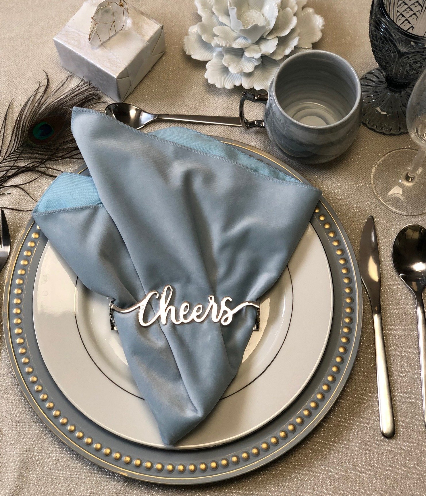 Cheers Wrap Set of 4 shiny silver napkin wraps elegantly displayed on a dining table.