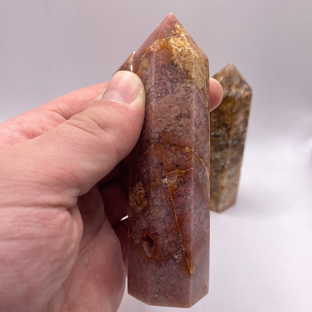 A polished Cherry Agate point showcasing its reddish-brown color and smooth surface, reflecting light beautifully.