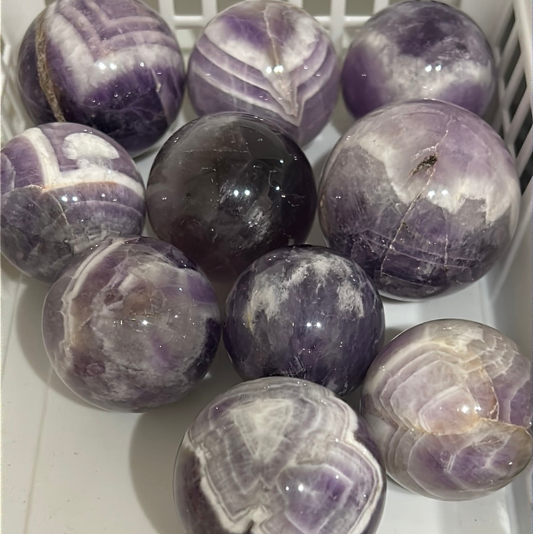 A beautiful Chevron Amethyst Sphere showcasing unique purple banding and natural crystal formations, symbolizing peace and healing.