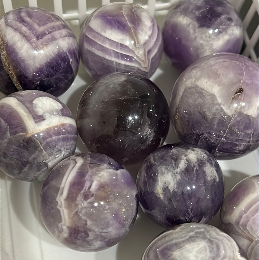 A beautiful Chevron Amethyst Sphere showcasing unique purple banding and natural crystal formations, symbolizing peace and healing.