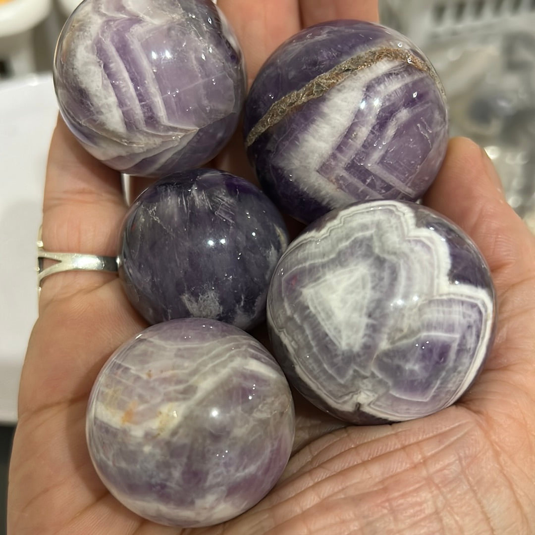 A beautiful Chevron Amethyst Sphere showcasing unique purple banding and natural crystal formations, symbolizing peace and healing.