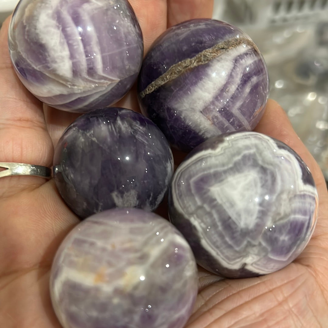 A beautiful Chevron Amethyst Sphere showcasing unique purple banding and natural crystal formations, symbolizing peace and healing.