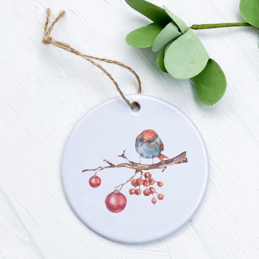 A beautifully crafted porcelain Christmas ornament featuring a branch with a bird design, showcasing vibrant colors and a glossy finish.