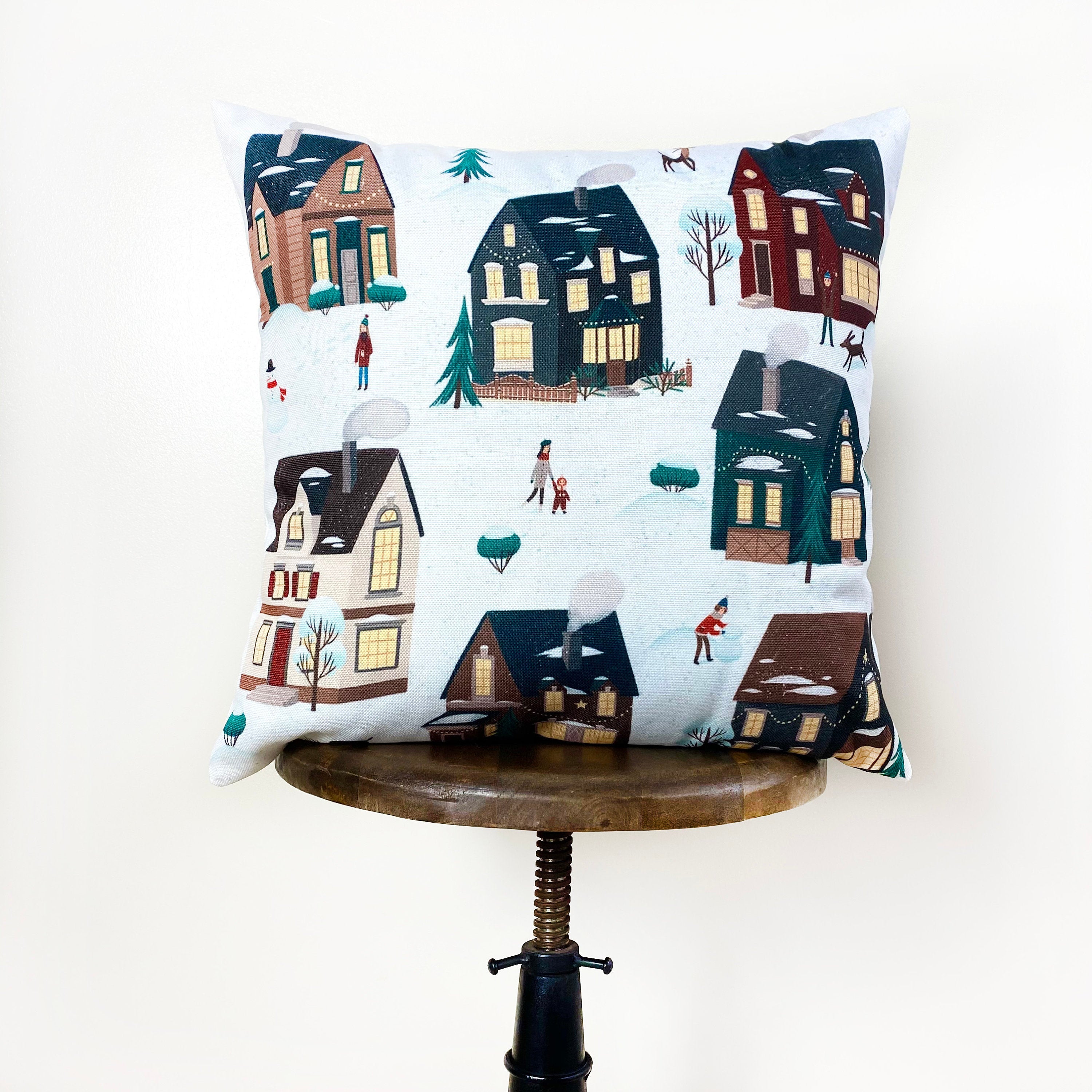 Christmas Village Houses Throw Pillow Cover featuring a snowy village scene with houses and neighbors, made in America.