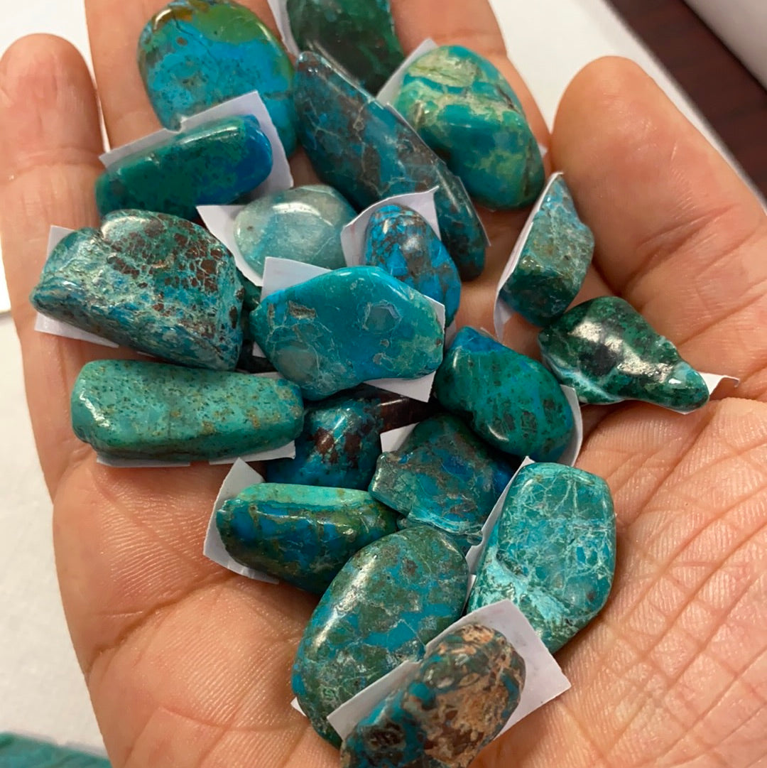 A collection of beautiful Chrysocolla tumbled stones in various shades of blue and green, showcasing their smooth, polished surfaces.