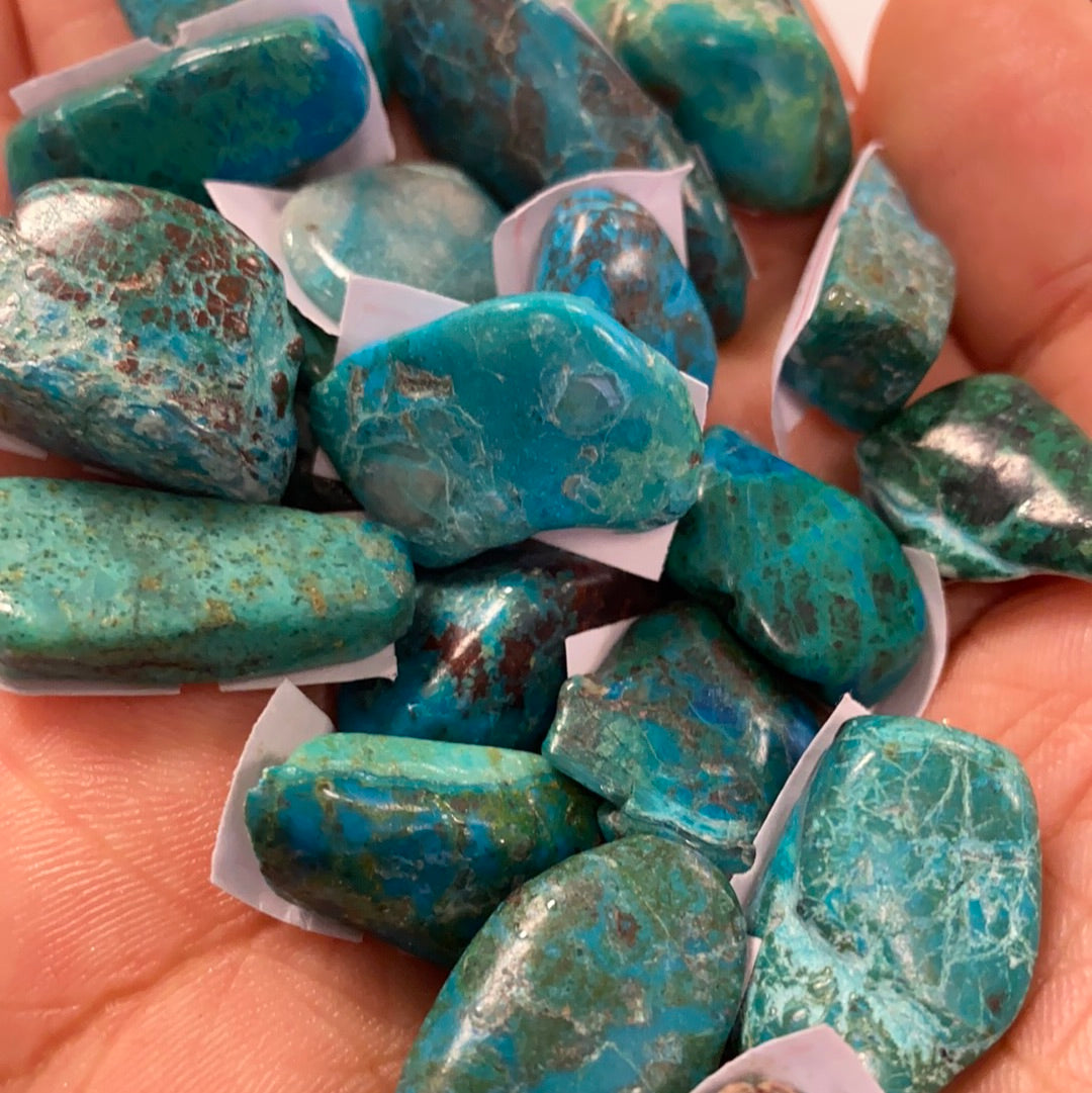 A collection of beautiful Chrysocolla tumbled stones in various shades of blue and green, showcasing their smooth, polished surfaces.