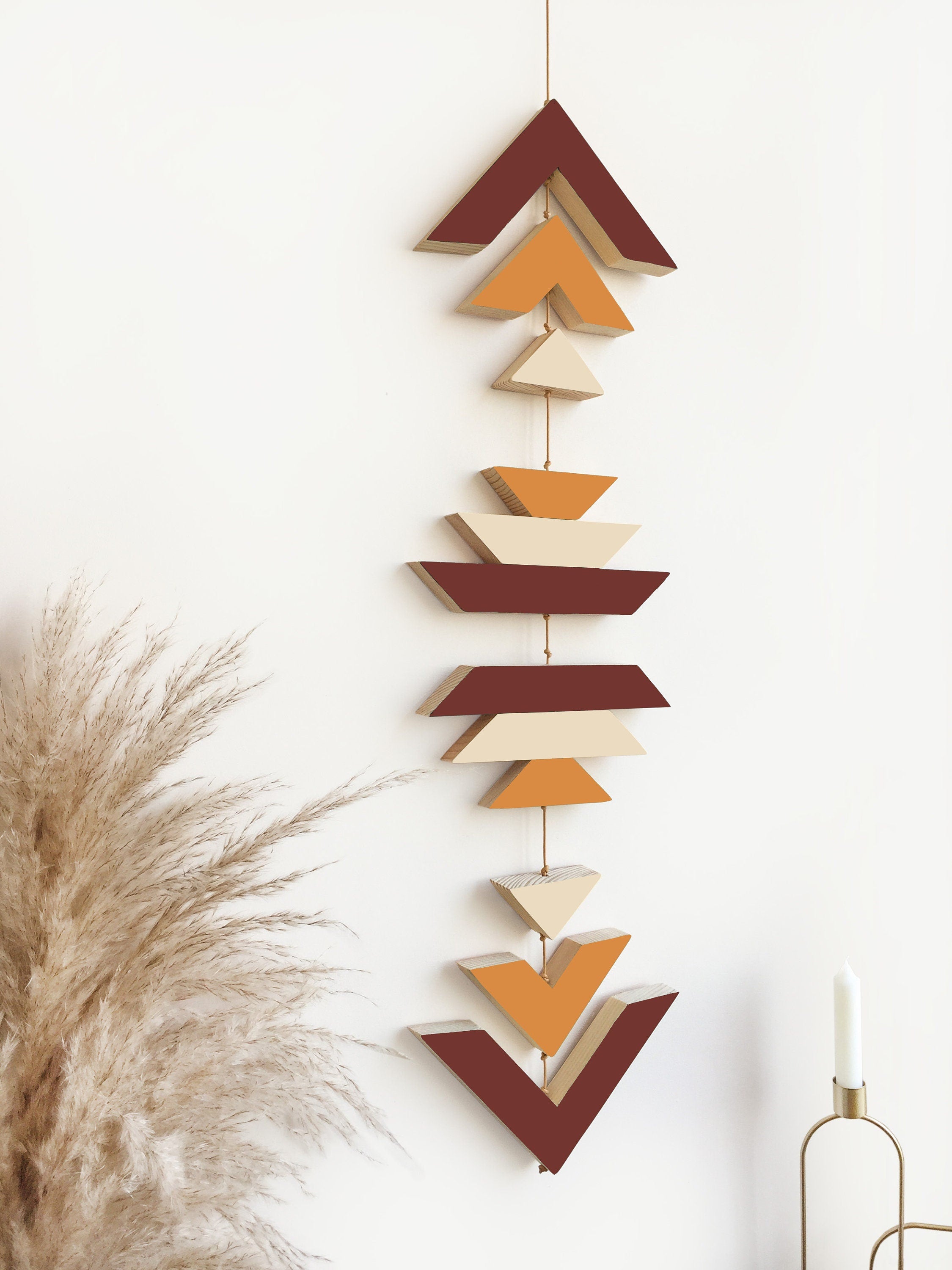 A beautiful cinnamon wood wall hanging featuring geometric designs, connected with cream cotton cord, perfect for boho decor.