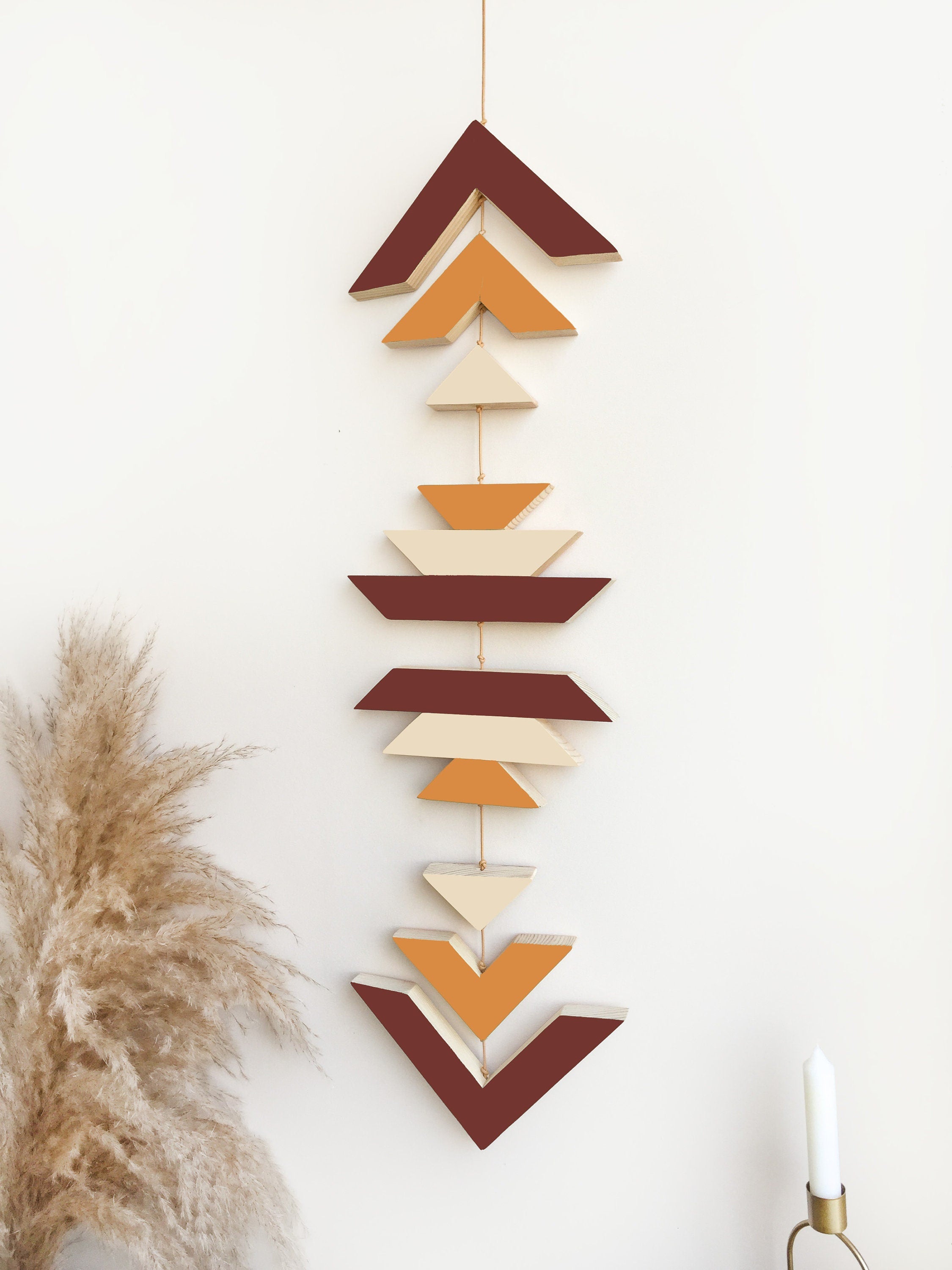 A beautiful cinnamon wood wall hanging featuring geometric designs, connected with cream cotton cord, perfect for boho decor.