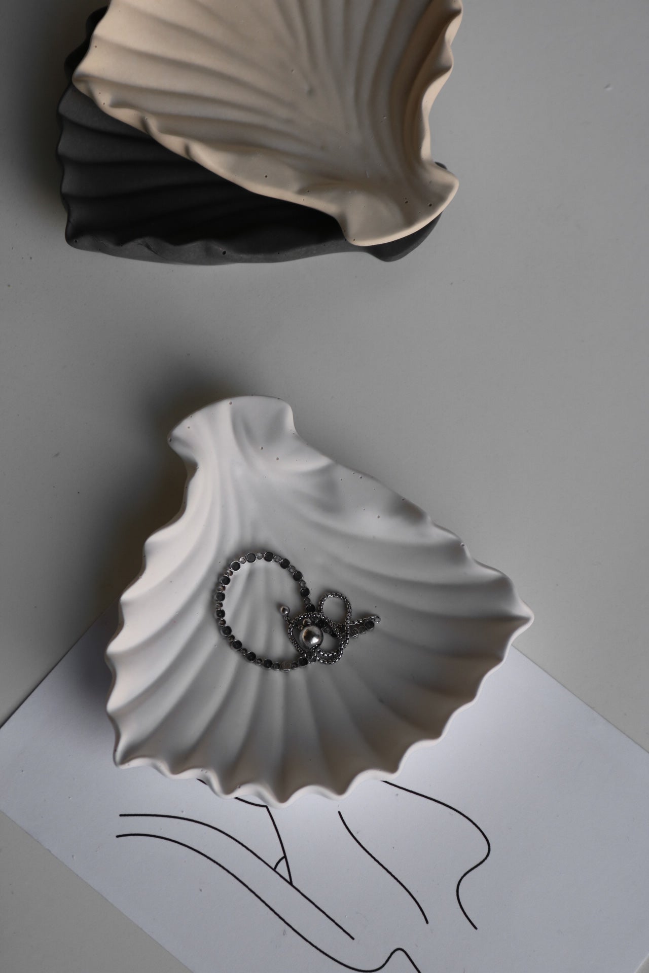 A hand-made clam shell jewellery dish in a soft color, showcasing its unique texture and elegant design, perfect for storing trinkets.