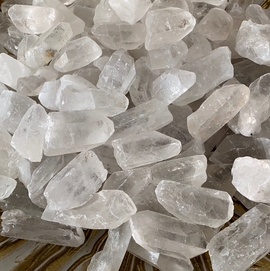 A collection of Clear Quartz Points showcasing various sizes and shapes, each with a pointed end, reflecting light beautifully.