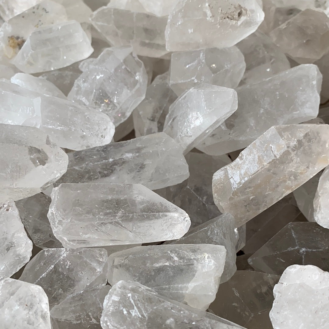 A collection of Clear Quartz Points showcasing various sizes and shapes, each with a pointed end, reflecting light beautifully.