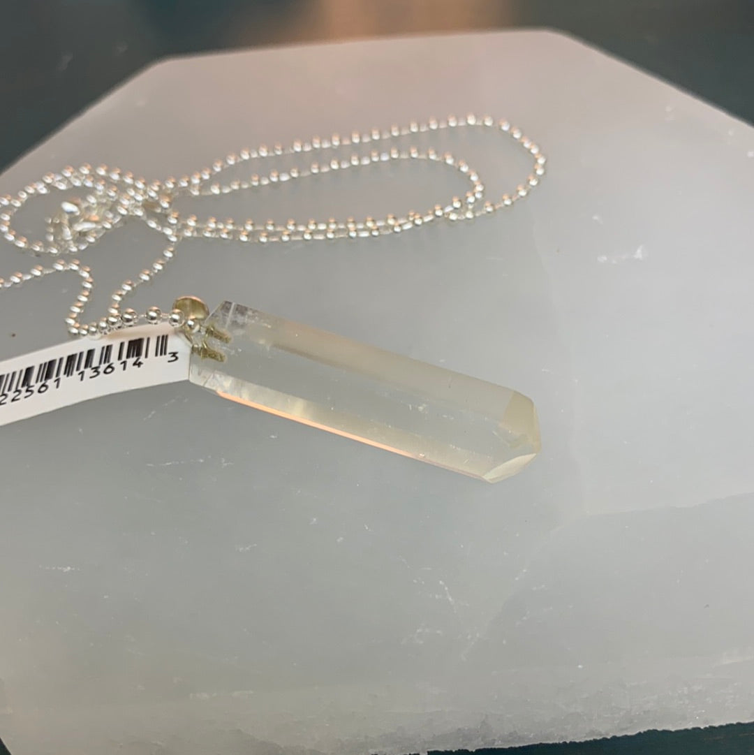 A beautifully faceted clear quartz point pendant, polished and attached to a bale, showcasing its clarity and shine.