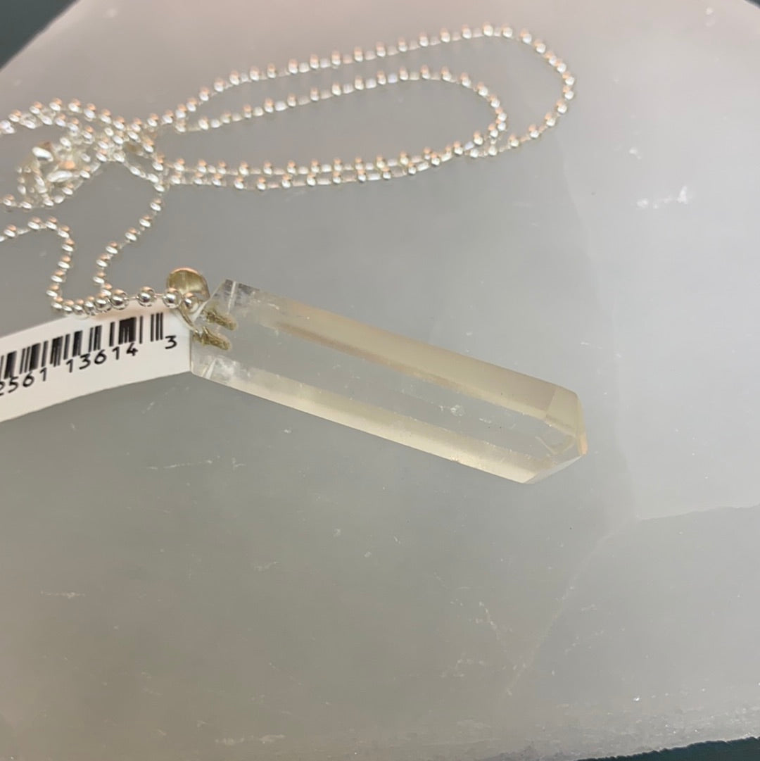 A beautifully faceted clear quartz point pendant, polished and attached to a bale, showcasing its clarity and shine.