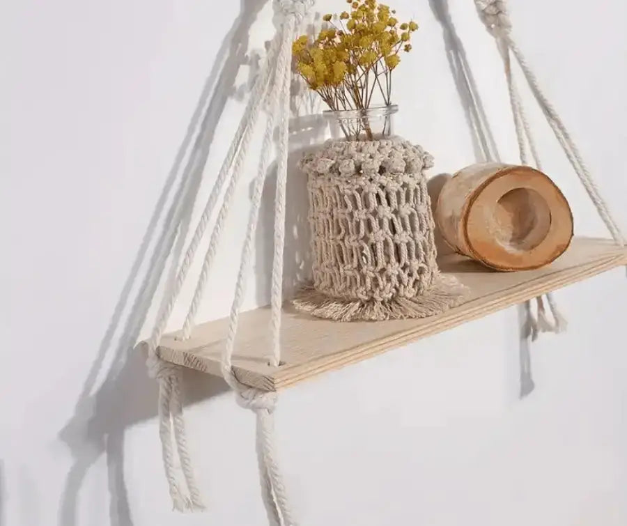 A beautifully handwoven cotton rope wall tapestry plant holder in beige, showcasing intricate knots and designed to hold plants.