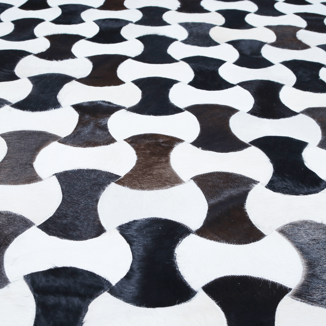 Hand-stitched cow skin rug with a modern curve pattern, showcasing natural leather texture and luxurious design.