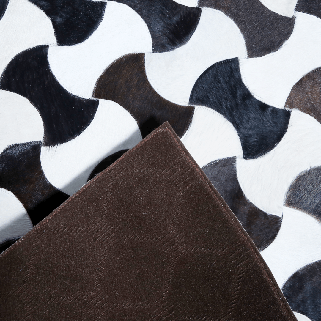 Hand-stitched cow skin rug with a modern curve pattern, showcasing natural leather texture and luxurious design.