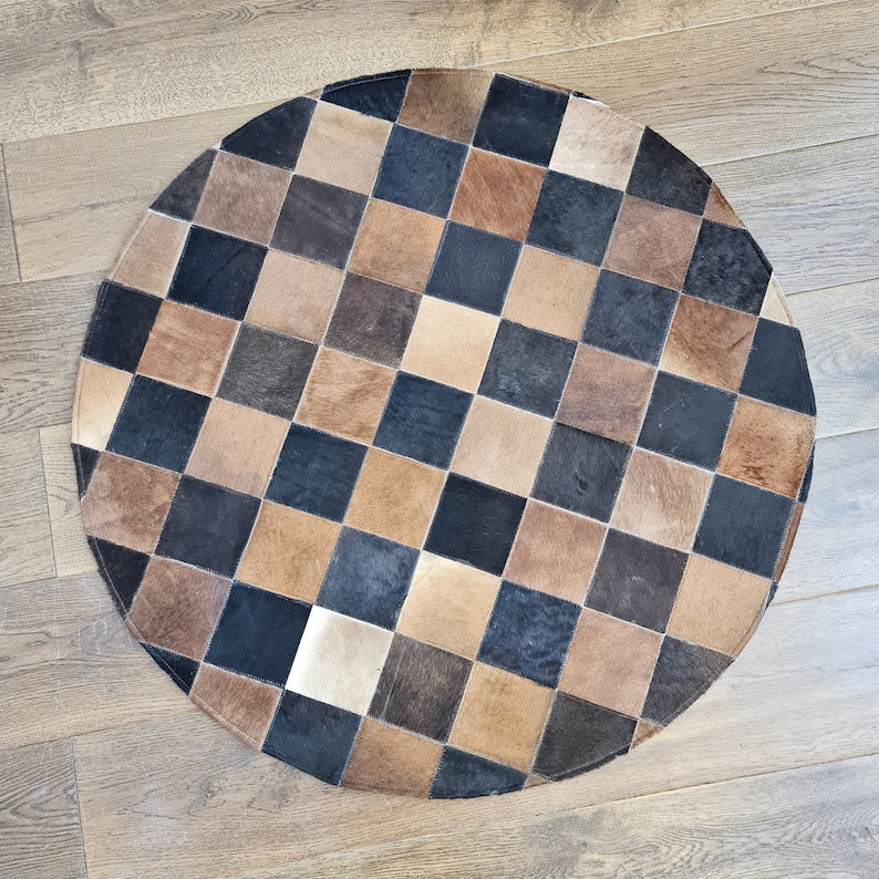 A luxurious round patchwork cow skin rug, showcasing unique leather patterns and textures, perfect for modern home decor.