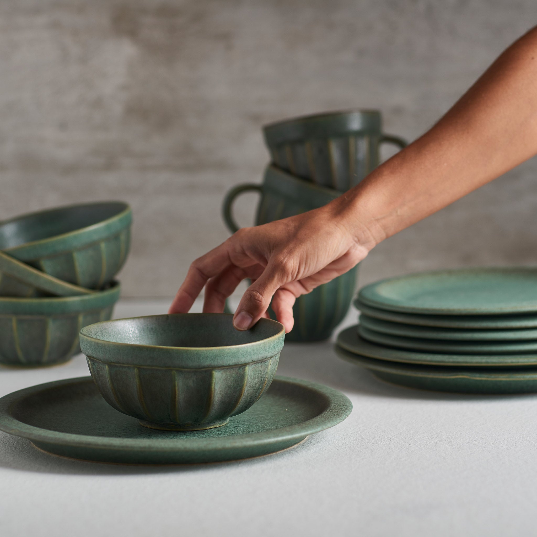 A handmade stoneware bowl with a beautiful green matte glaze, showcasing unique imperfections and a stylish design.