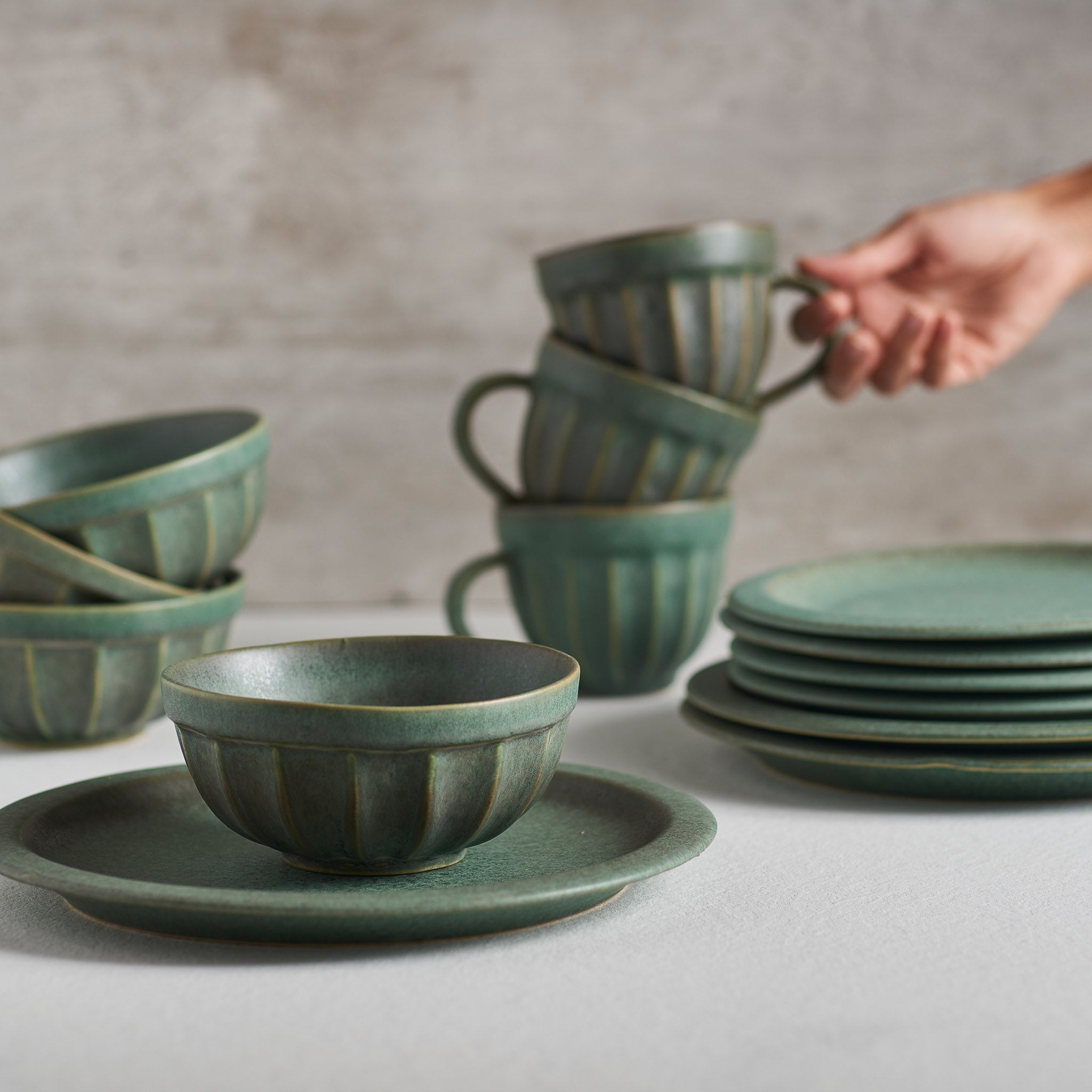 A handmade stoneware bowl with a beautiful green matte glaze, showcasing unique imperfections and a stylish design.