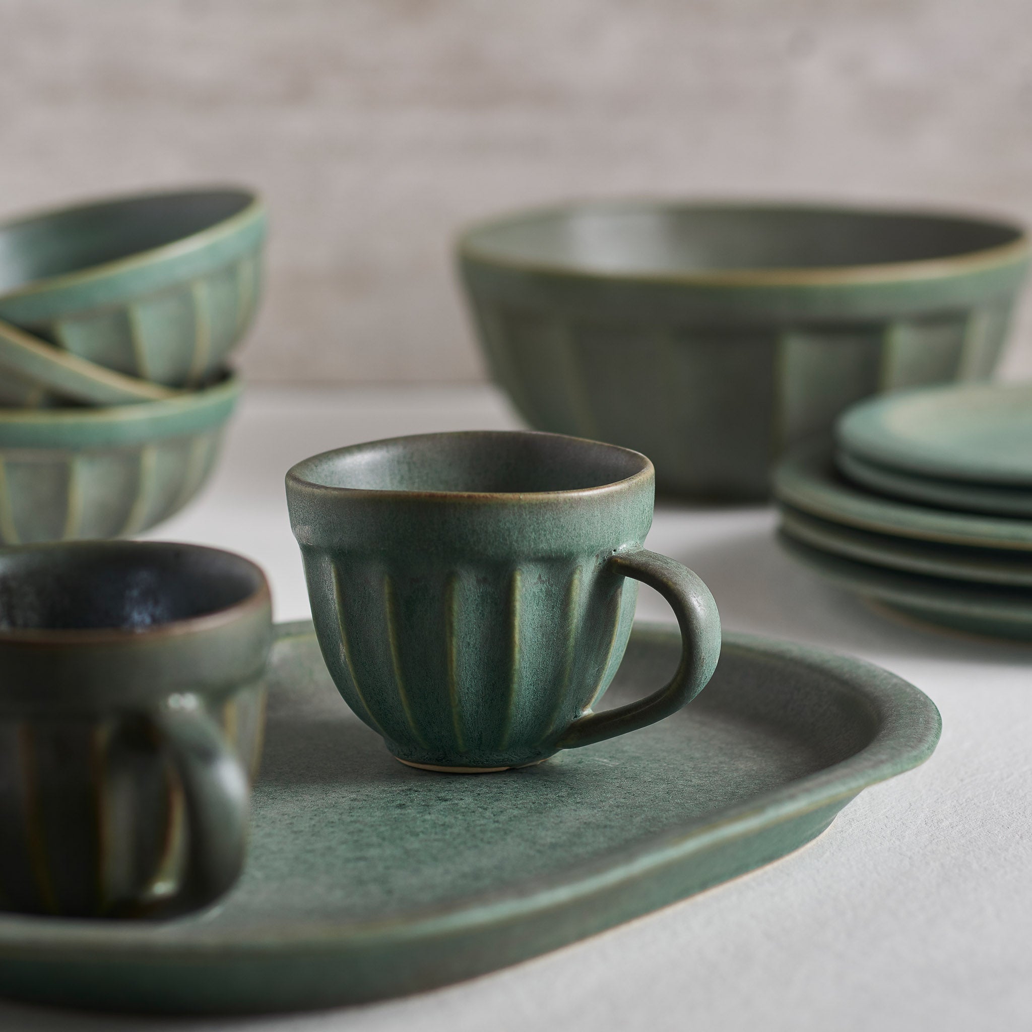 A handmade stoneware bowl with a beautiful green matte glaze, showcasing unique imperfections and a stylish design.