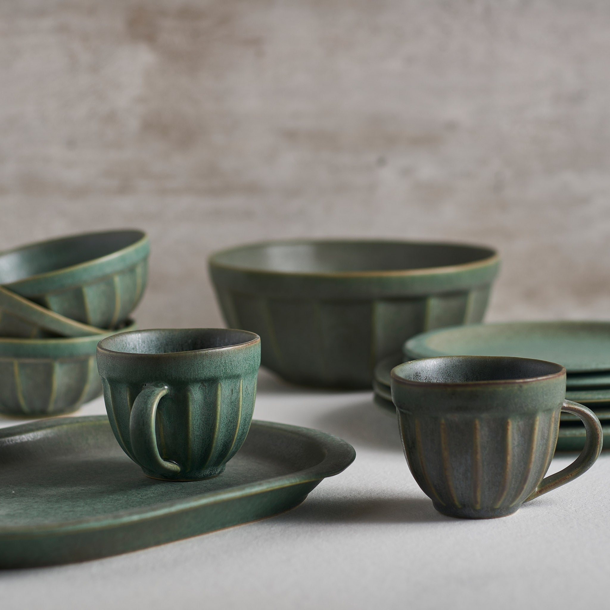 A handmade stoneware bowl with a beautiful green matte glaze, showcasing unique imperfections and a stylish design.