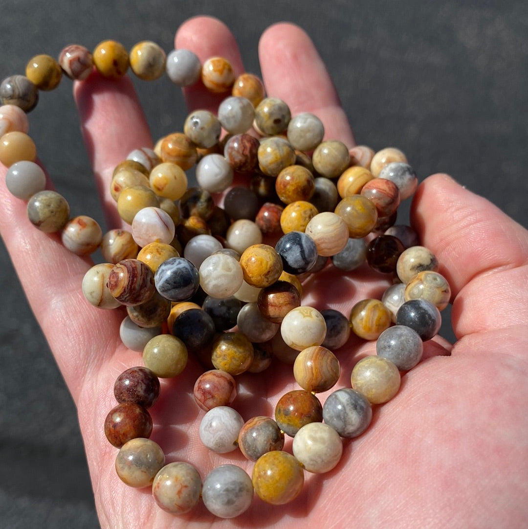 A stunning 8mm Crazy Lace Agate Bracelet featuring unique swirls and stripes in white, gray, and brown, symbolizing beauty and metaphysical energy.