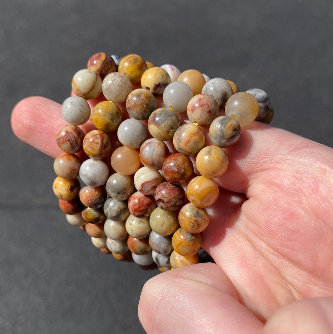 A stunning 8mm Crazy Lace Agate Bracelet featuring unique swirls and stripes in white, gray, and brown, symbolizing beauty and metaphysical energy.