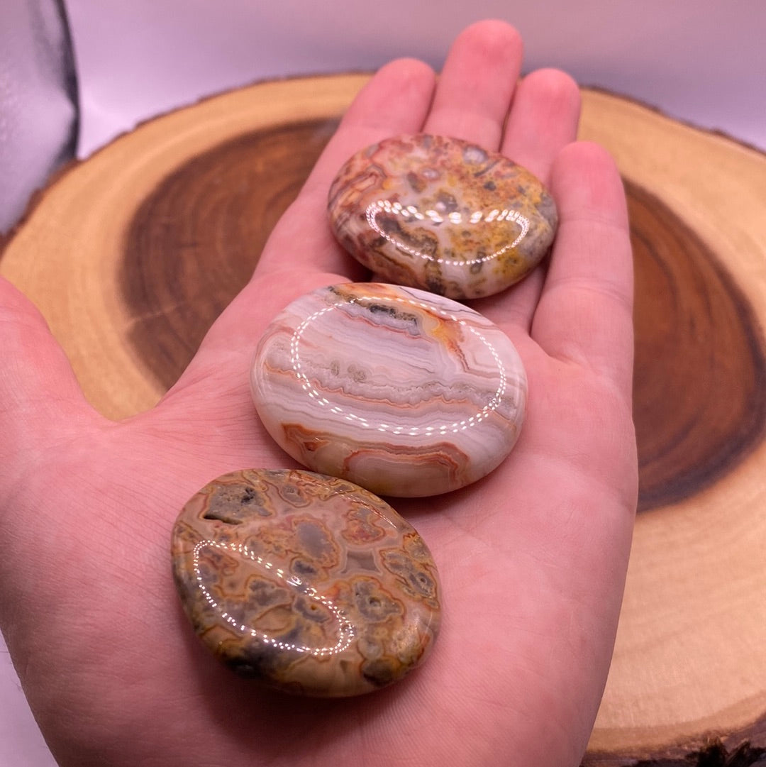 A beautiful Crazy Lace Agate Palm Stone showcasing creamy oranges, browns, and whites with a smooth surface, perfect for meditation.