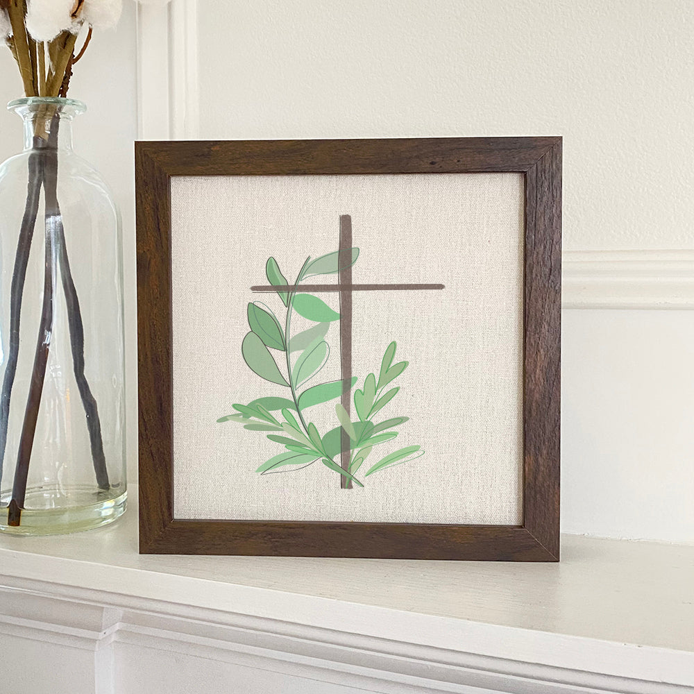 Framed sign featuring a cross with leaves, set in a stylish wood frame with a linen-look background.