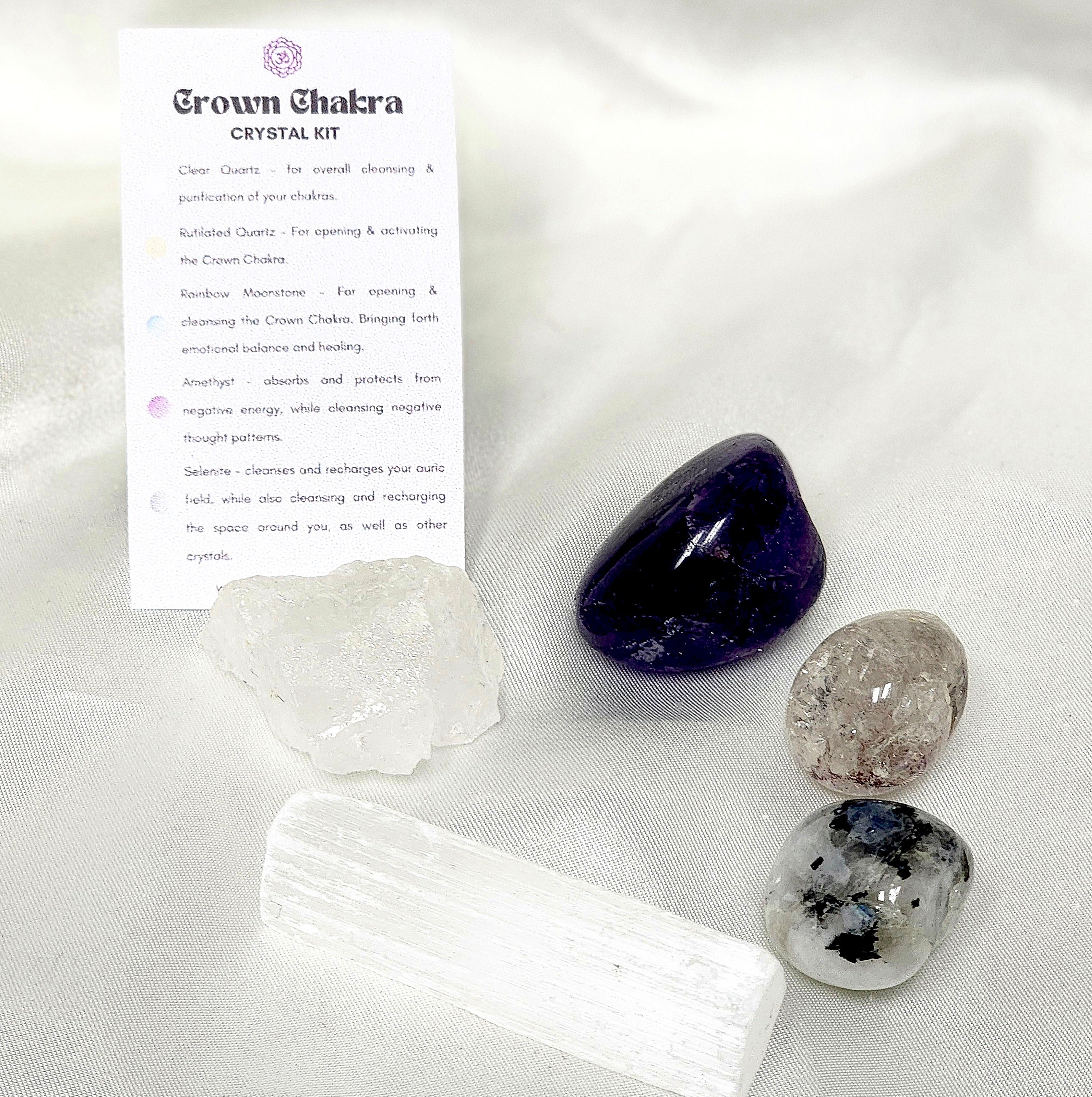 Crown Chakra Crystal Kit featuring Clear Quartz, Rutilated Quartz, Rainbow Moonstone, Amethyst, and Selenite arranged aesthetically.