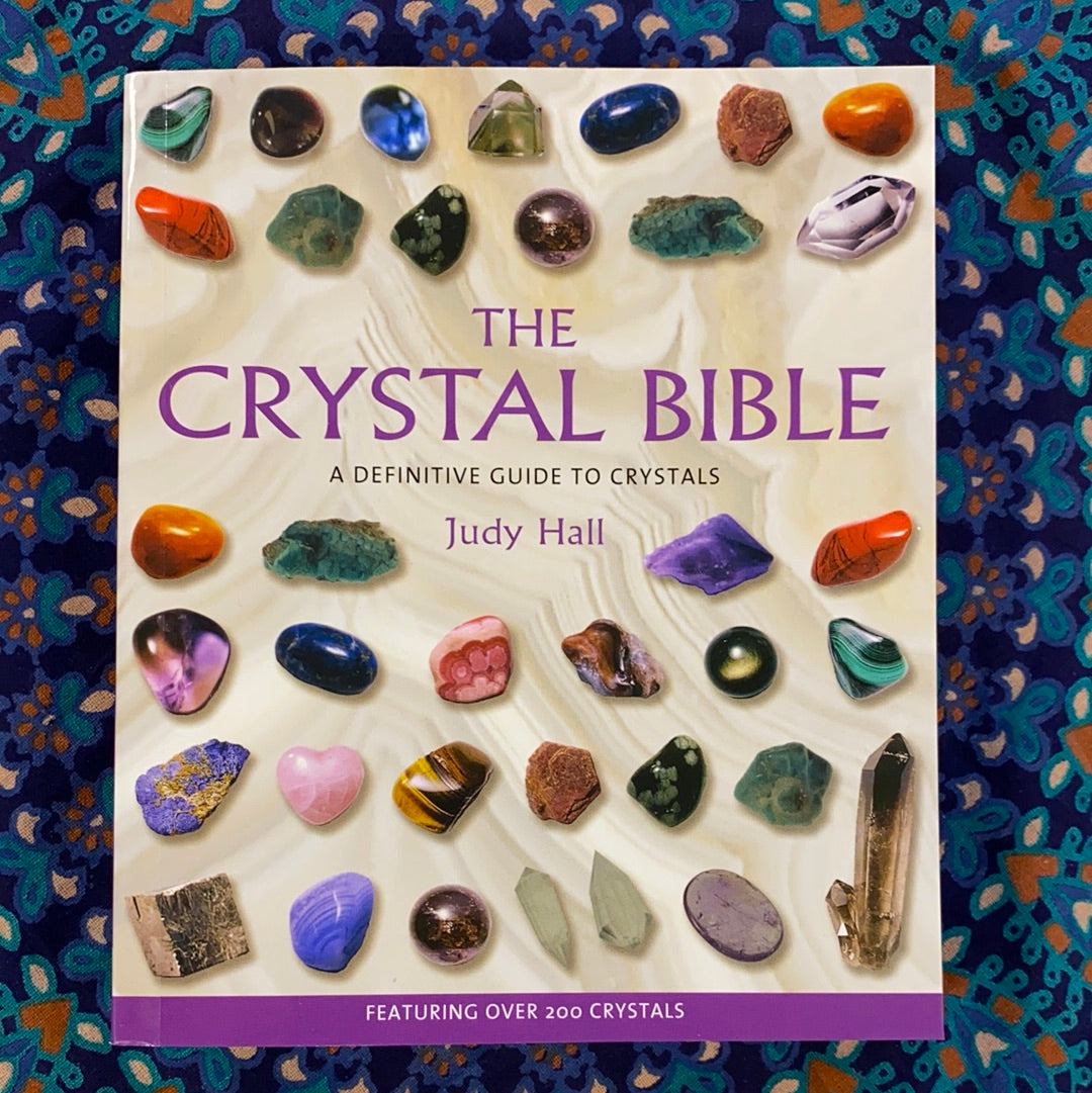 The Crystal Bible book cover featuring colorful illustrations of various crystals and gemstones.