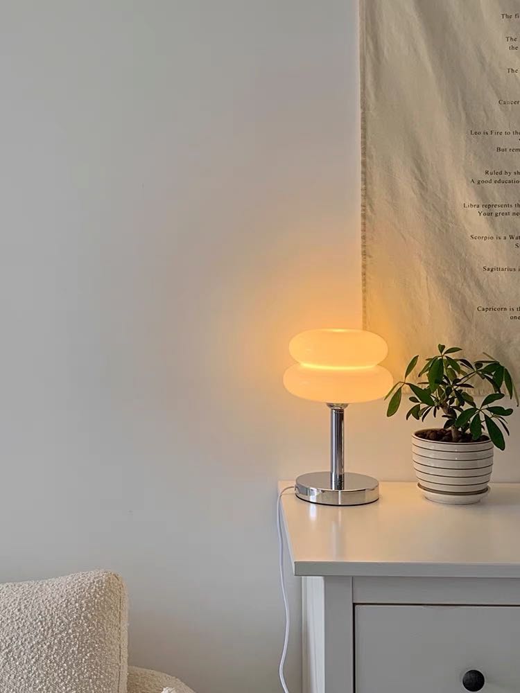 A cute chubby fluffy bedside lamp shaped like a cloud, emitting a warm glow, perfect for creating a cozy atmosphere.