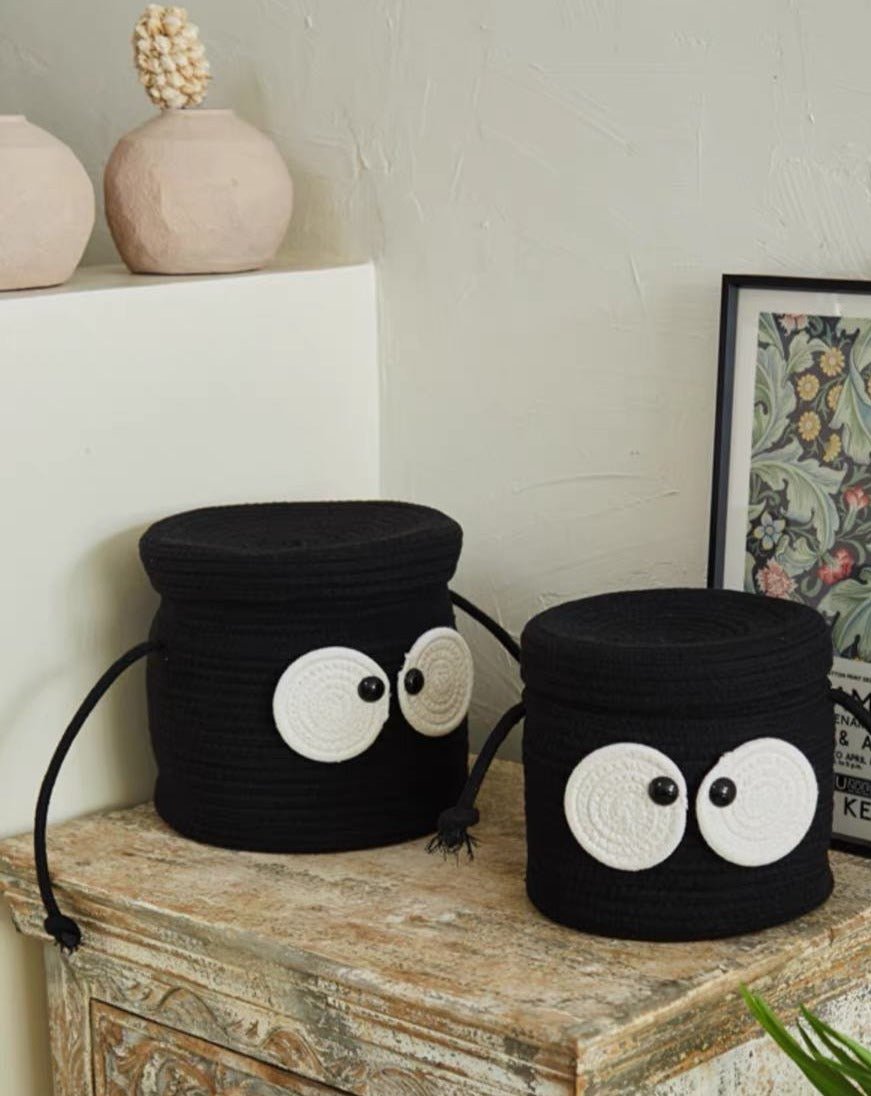 A cute woven laundry storage basket featuring a coal ball design with big eyes, perfect for kids' rooms and playful spaces.