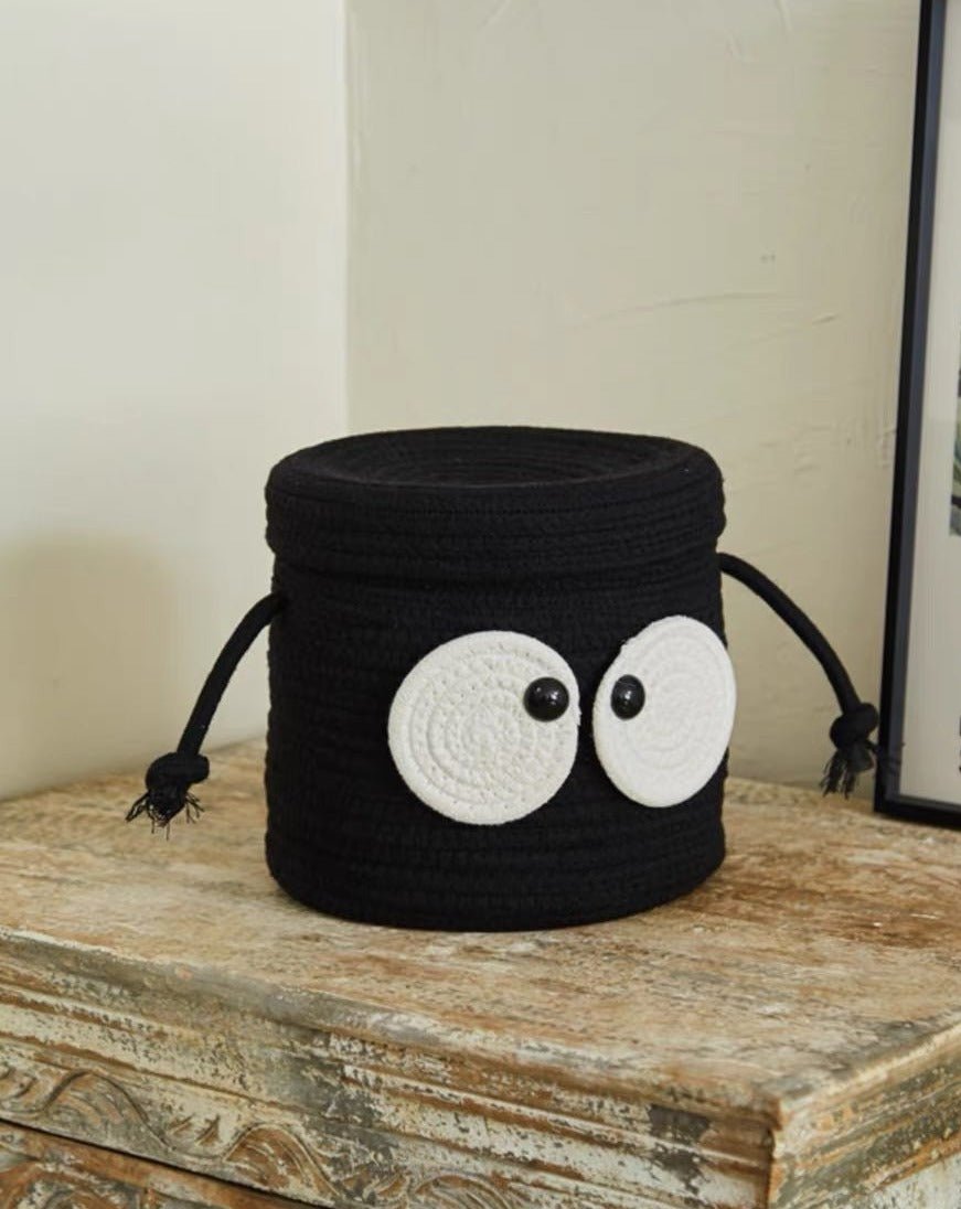 A cute woven laundry storage basket featuring a coal ball design with big eyes, perfect for kids' rooms and playful spaces.