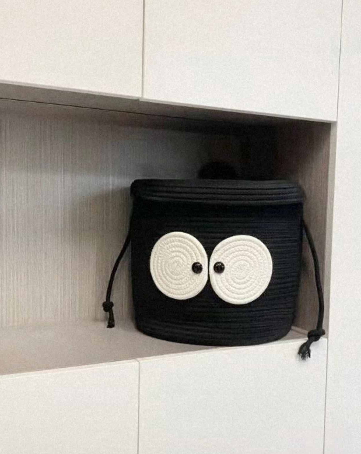 A cute woven laundry storage basket featuring a coal ball design with big eyes, perfect for kids' rooms and playful spaces.