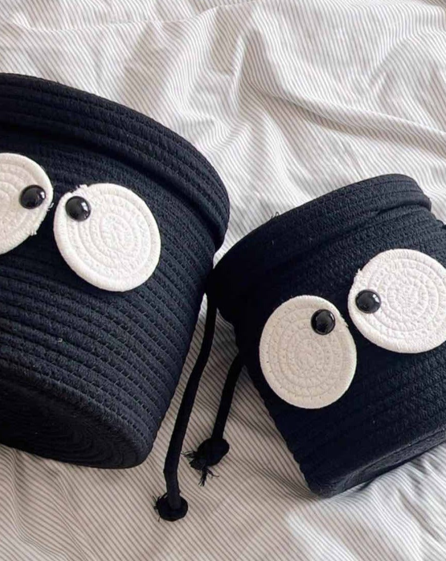 A cute woven laundry storage basket featuring a coal ball design with big eyes, perfect for kids' rooms and playful spaces.