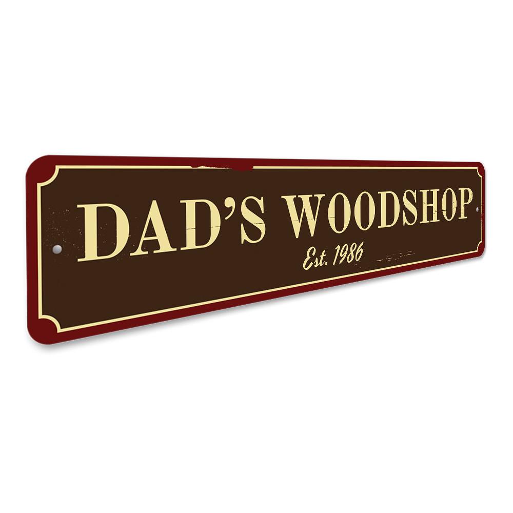 A decorative Dad's Woodshop Sign made of high-quality aluminum, featuring customizable text and pre-drilled holes for easy mounting.