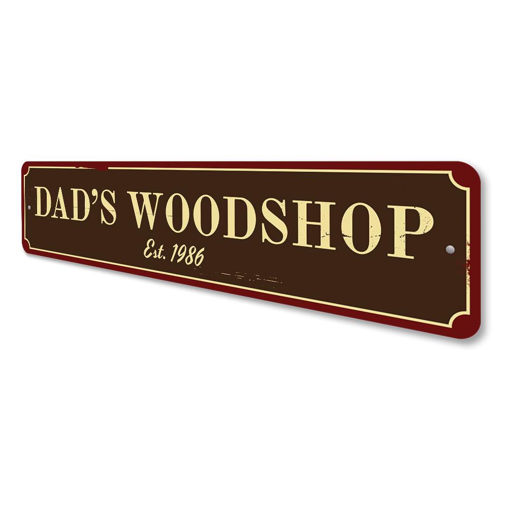 A decorative Dad's Woodshop Sign made of high-quality aluminum, featuring customizable text and pre-drilled holes for easy mounting.