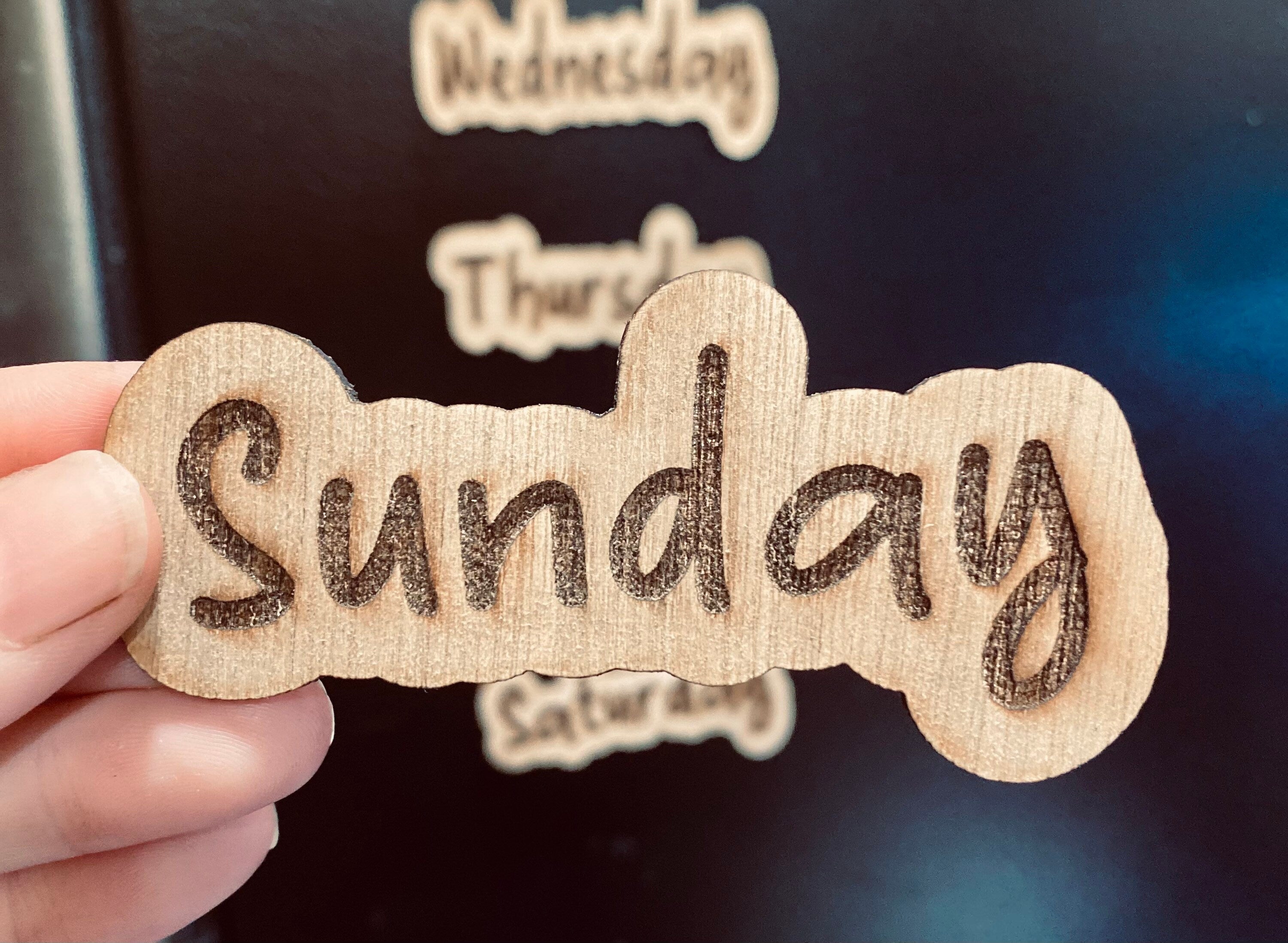 Set of wooden Days of the Week Magnets displayed on a fridge, showcasing their natural finish and laser engraved design.