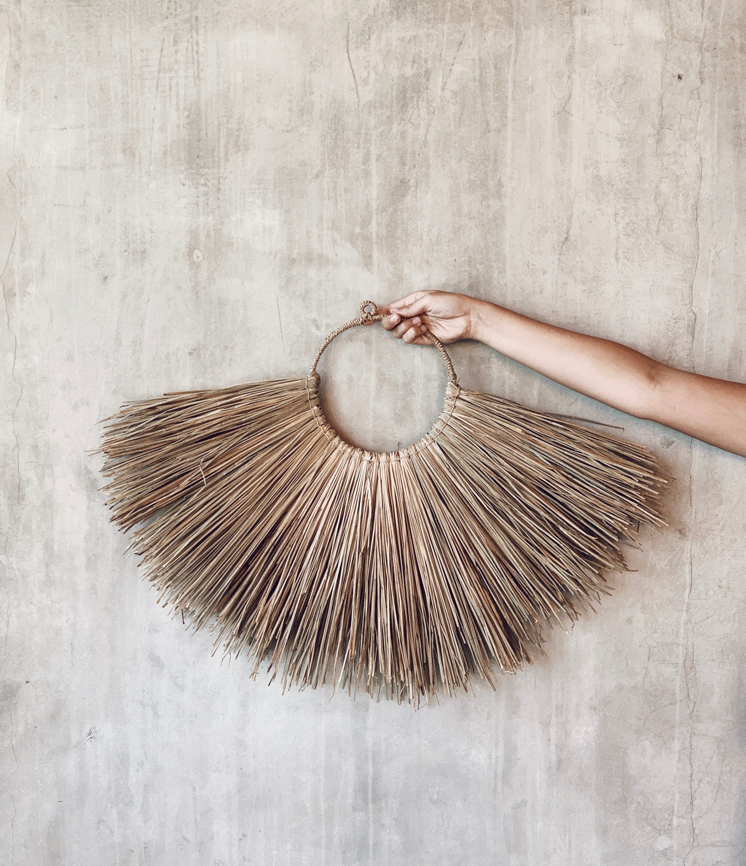 Jingga Allang wall decoration made of natural grass, showcasing intricate weaving and bohemian style.