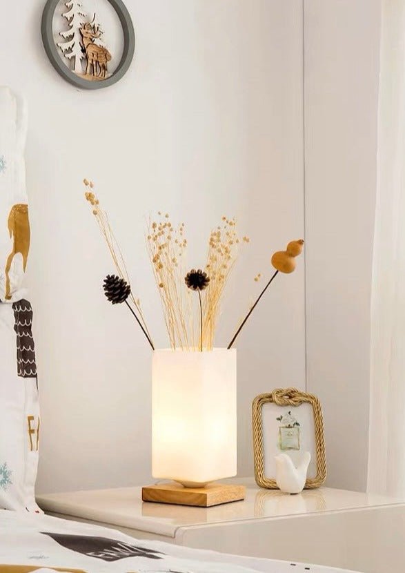 A stylish dimmable flower vase beside a decorative table lamp featuring a frosted glass body and a wooden base, perfect for rustic home decor.