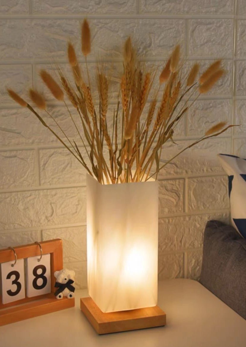 A stylish dimmable flower vase beside a decorative table lamp featuring a frosted glass body and a wooden base, perfect for rustic home decor.