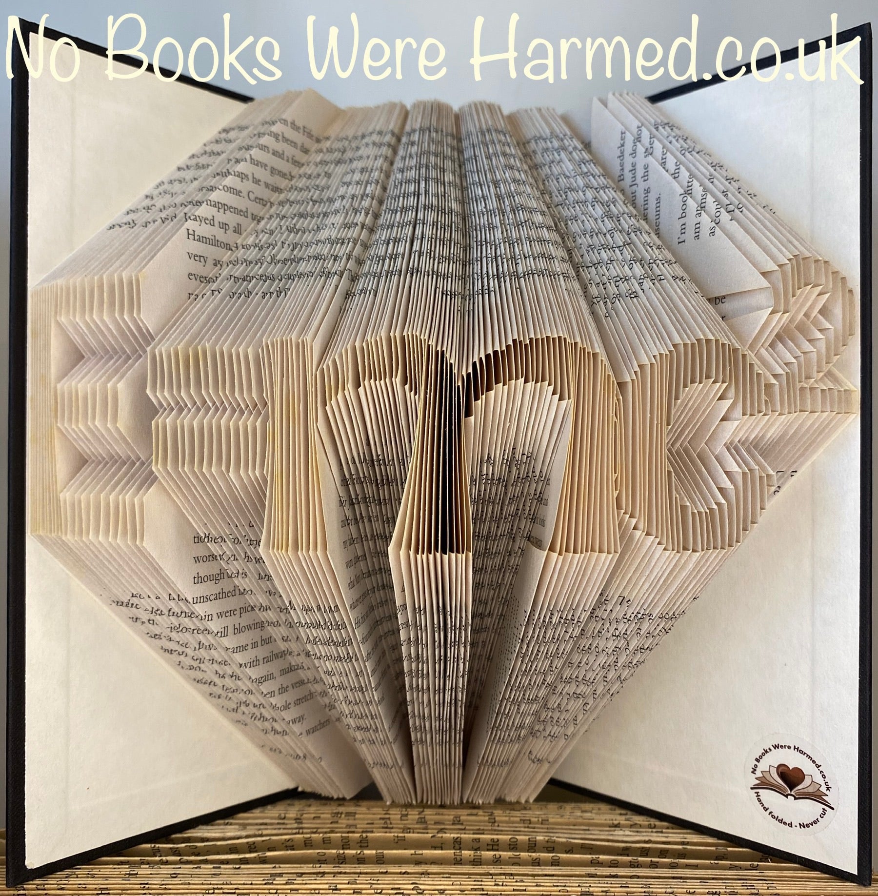 Handcrafted E=mc2 book art made from vintage books, showcasing intricate page folds and unique design.