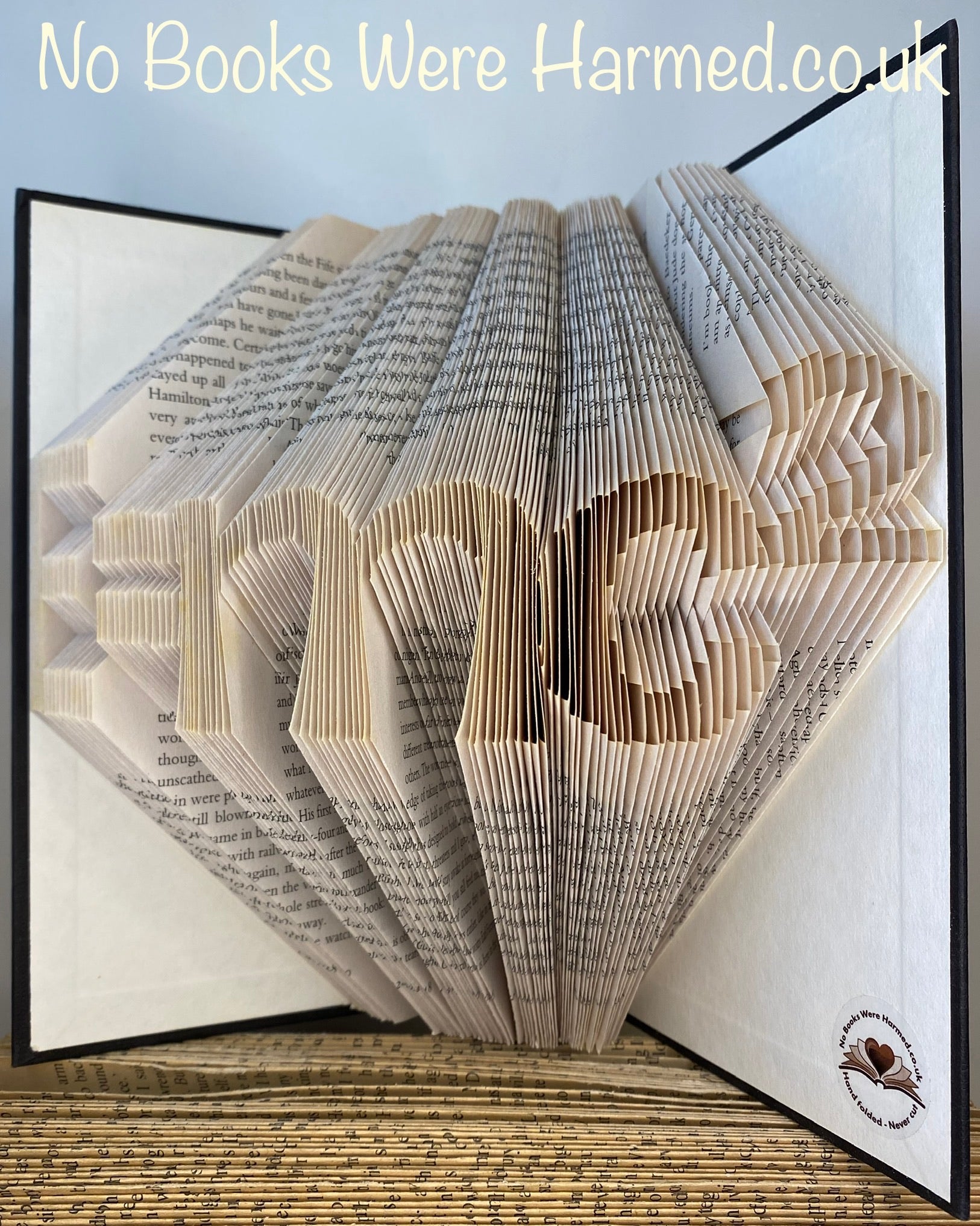 Handcrafted E=mc2 book art made from vintage books, showcasing intricate page folds and unique design.