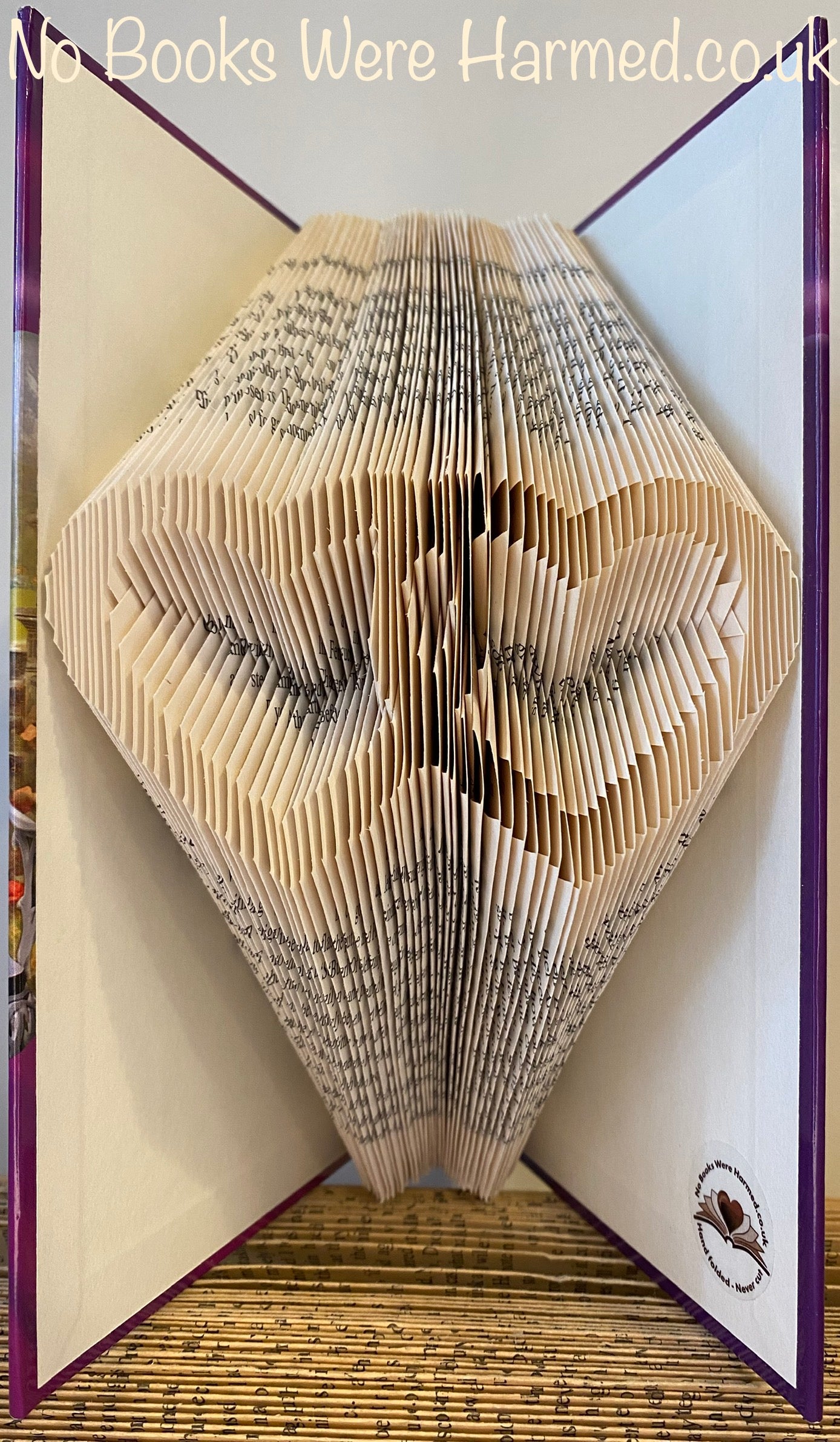 A beautifully crafted entwined love hearts art piece made from vintage book pages, showcasing intricate hand-folded designs.