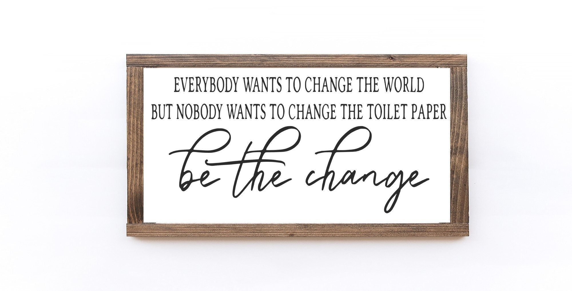 Handmade wooden sign with the phrase 'Be The Change' in matte white finish, showcasing unique wood grain and knots.