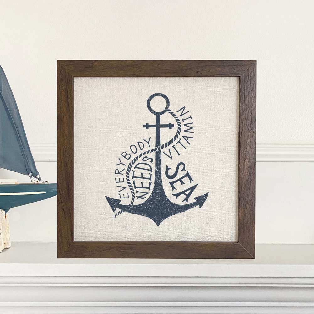 Framed sign reading 'Everyone Needs Vitamin Sea' with a stylish wood frame and linen-look background, perfect for home decor.