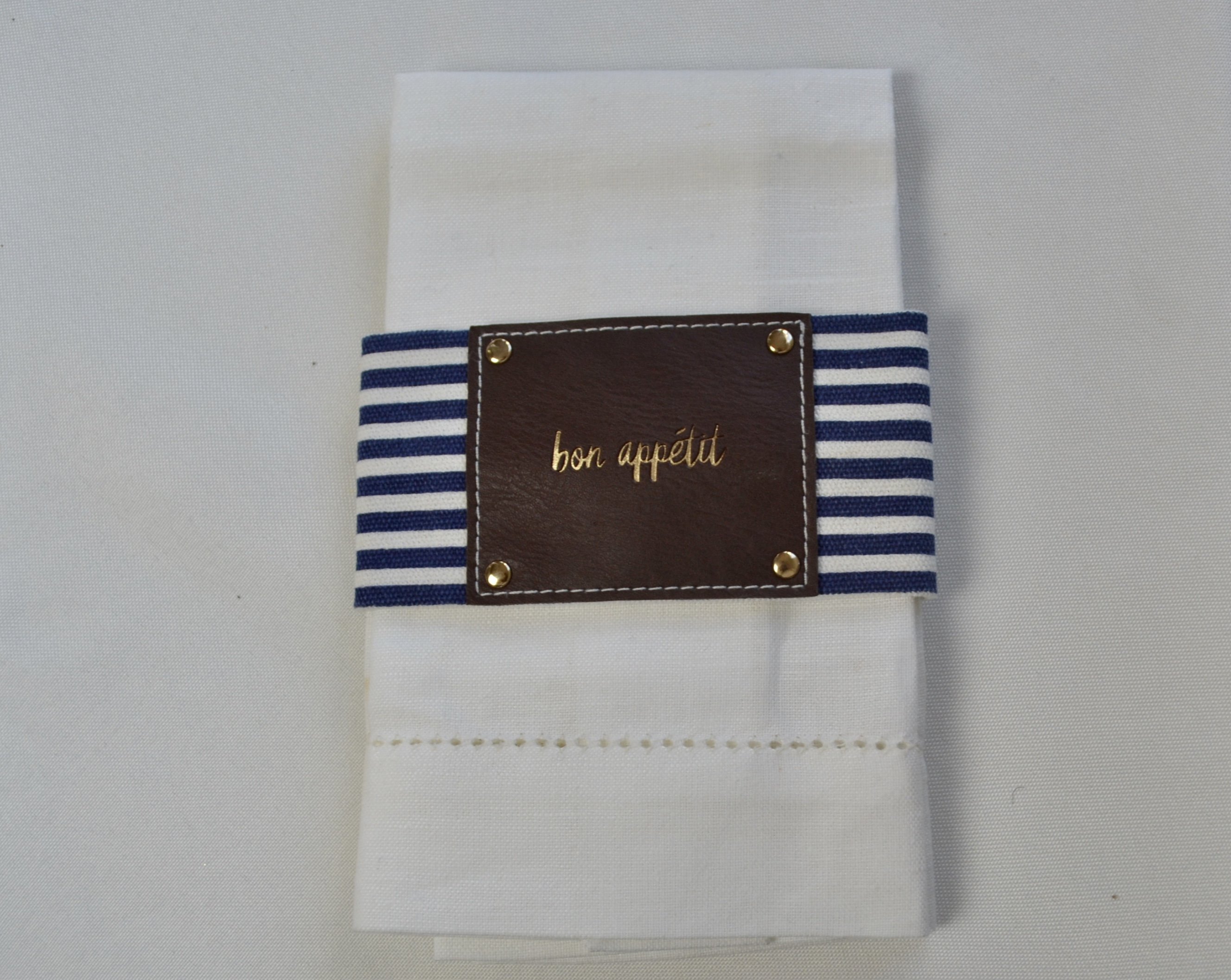 Navy stripe fabric and leather style napkin wrap elegantly displayed with a napkin.