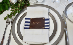 Navy stripe fabric and leather style napkin wrap elegantly displayed with a napkin.